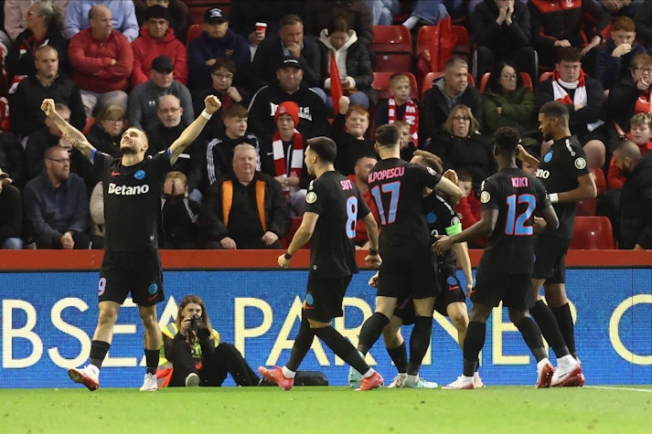 fotbaliști în echipament negru se bucură pe teren după un gol
