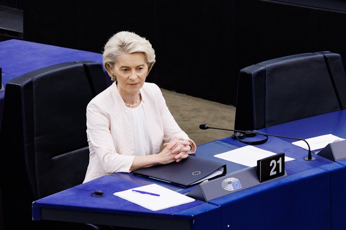Ursula von der Leyen așezată la un birou, cu mâinile una peste alta