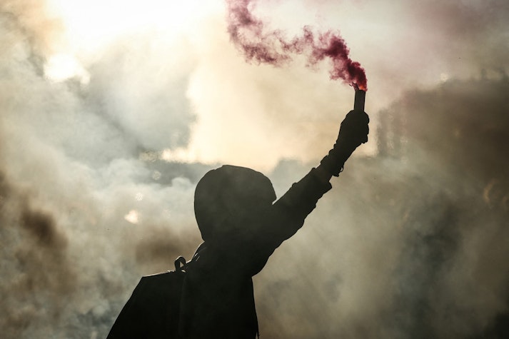 protestatar ține în mână o fumigenă