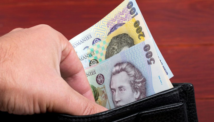 Taxe și impozite O mana scoate niste bancnote dintr-un portofel