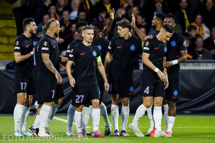 fotbaliști în echipament negru sărbătoresc pe teren un gol