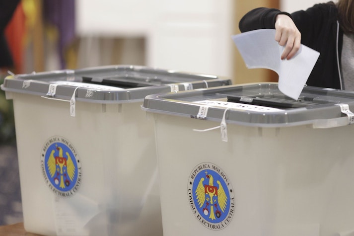 O femeie introduce un buletin de vot într-o urnă pentru alegerile din Moldova