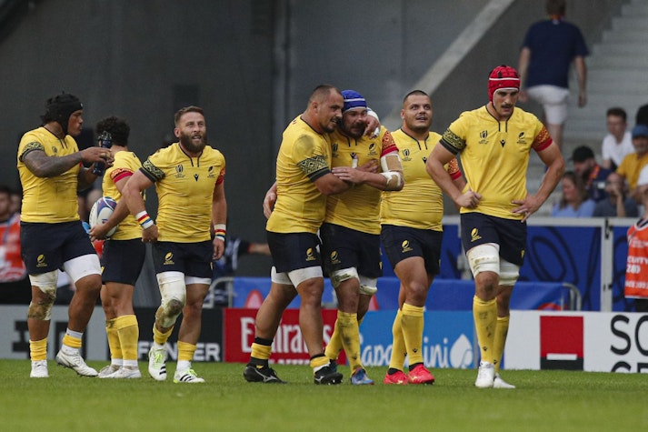 jucători de rugby pe teren, în echipament galben și albastru închis