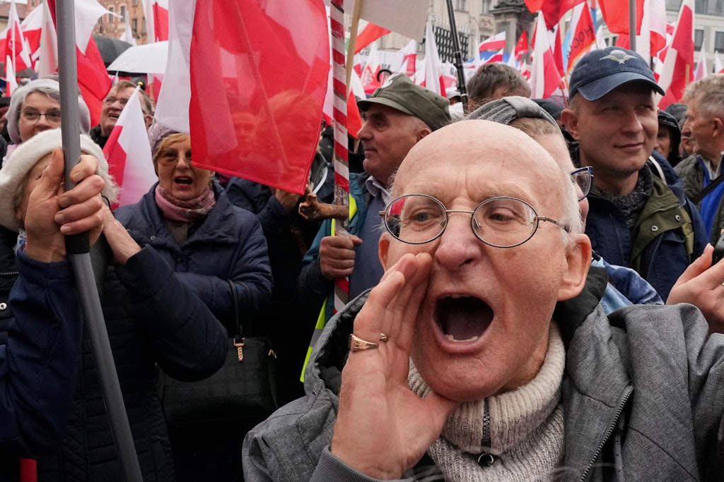 Bărbat în prim plan, în timpul protestului din Polonia. Mulțime de oameni cu steagurile Poloniei în spatele lui