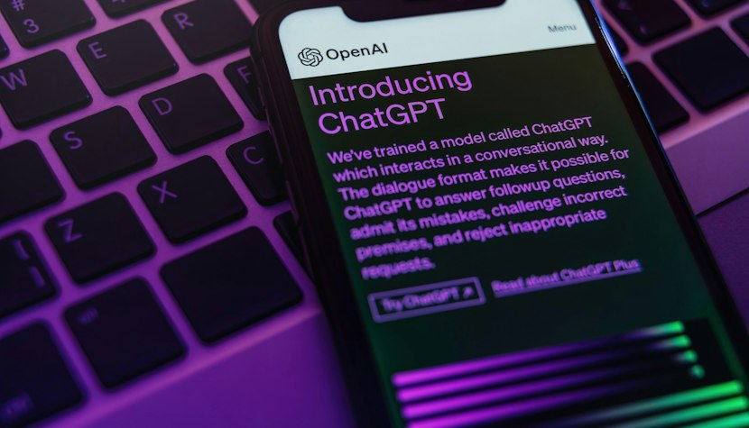 OpenAi a lansat browser propriu telefon așezat pe tastatura unui laptop și pe care este deschisă o pagină despre chatgpt