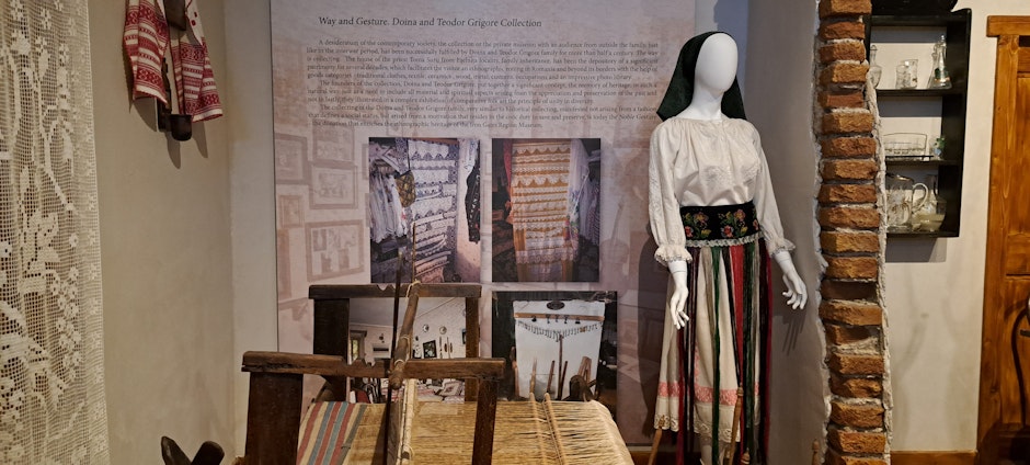expoziție cu un manechin îmbrăcat în costum popular românesc și un război de țesut tradițional