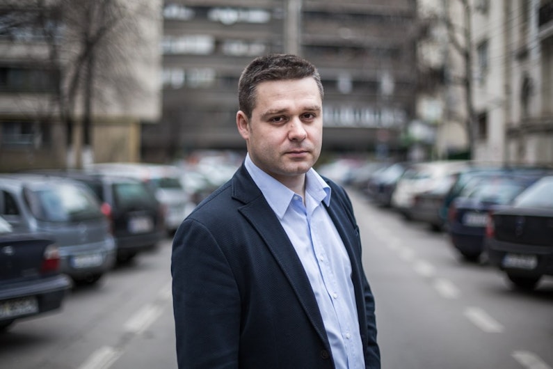 Ciprian Ciucu, la cămașă și sacou, privind spre fotograf, pe o stradă