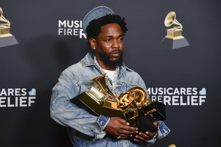 Kendrick Lamar ținând premii Grammy în mână