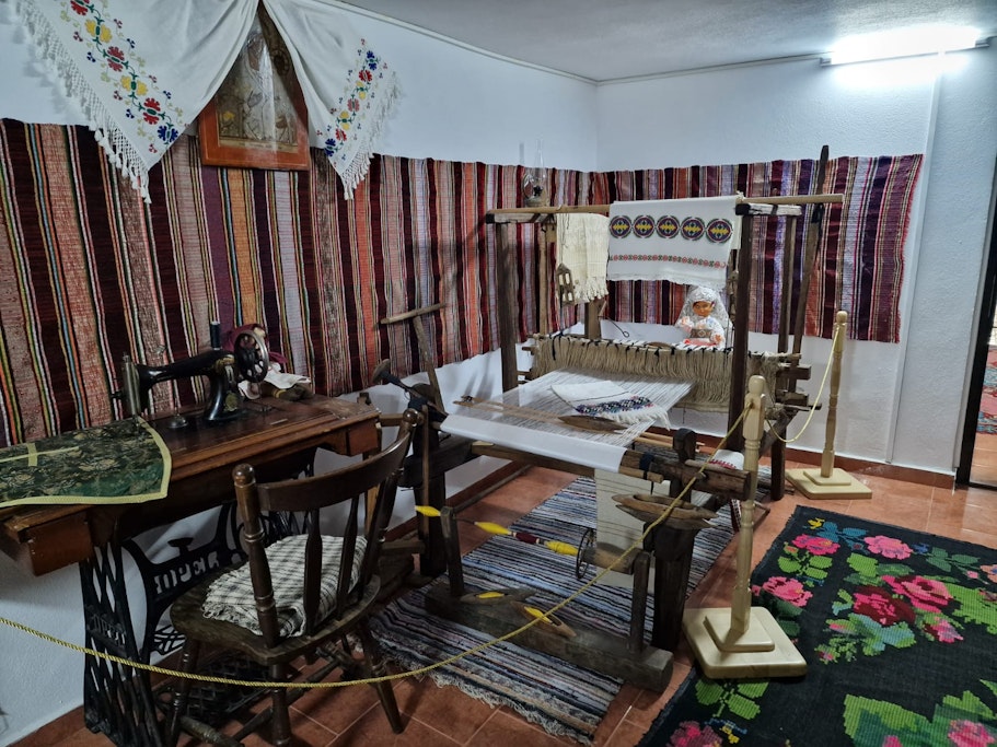 Expoziție etnografică la Mănăstirea Lacu Sărat, cu mașină de cusut veche, război de țesut și țesături tradiționale românești