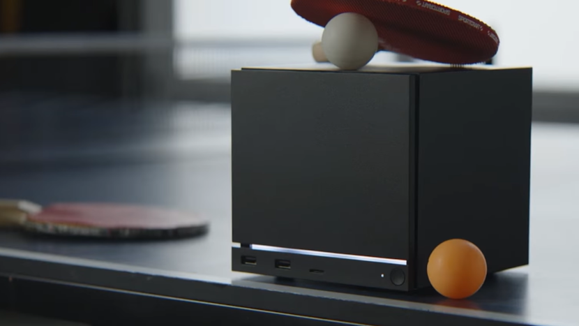 Consola Steam Machine pe o masă neagră cu 2 palete de ping-pong și două mingi de ping-pong