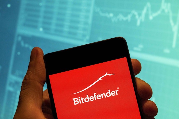 Poză cu o mână care ține un telefon în mână cu Bitdefender scris pe ecran.
