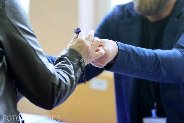 un bărbat îi dă unei alegătoare ștampila de vot