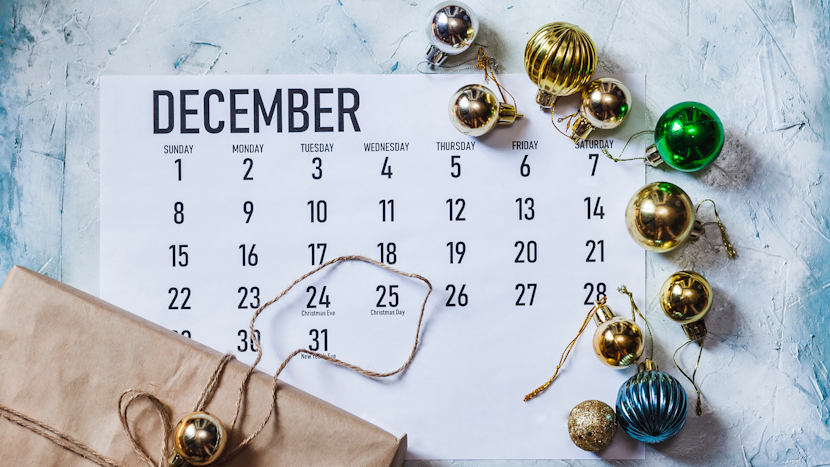 calendar al lunii decembrie, înconjurat de globuri de crăciun și o cutie de cadouri