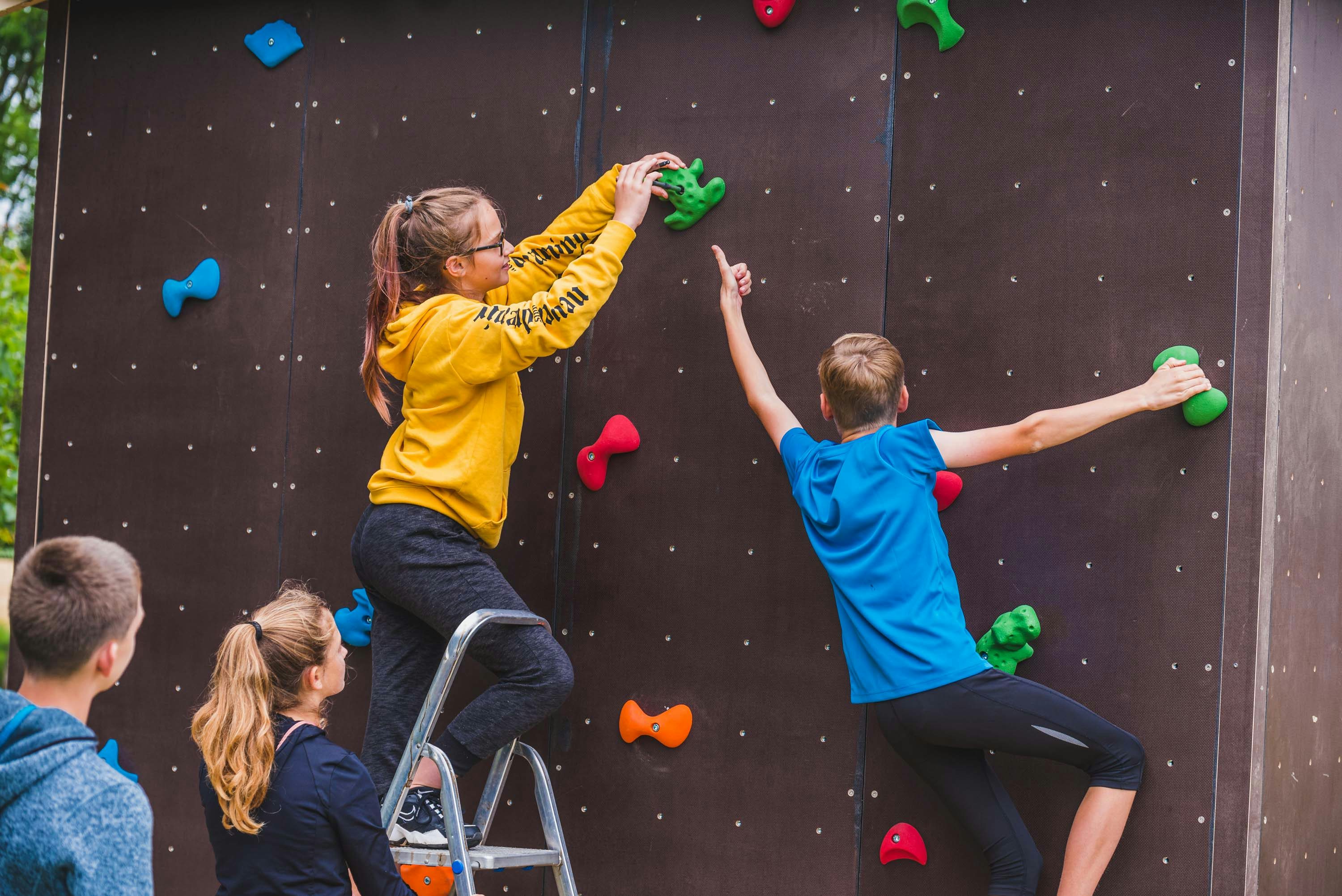 Zwei Mädchen und zwei Jungen bauen einen Boulderzusammen