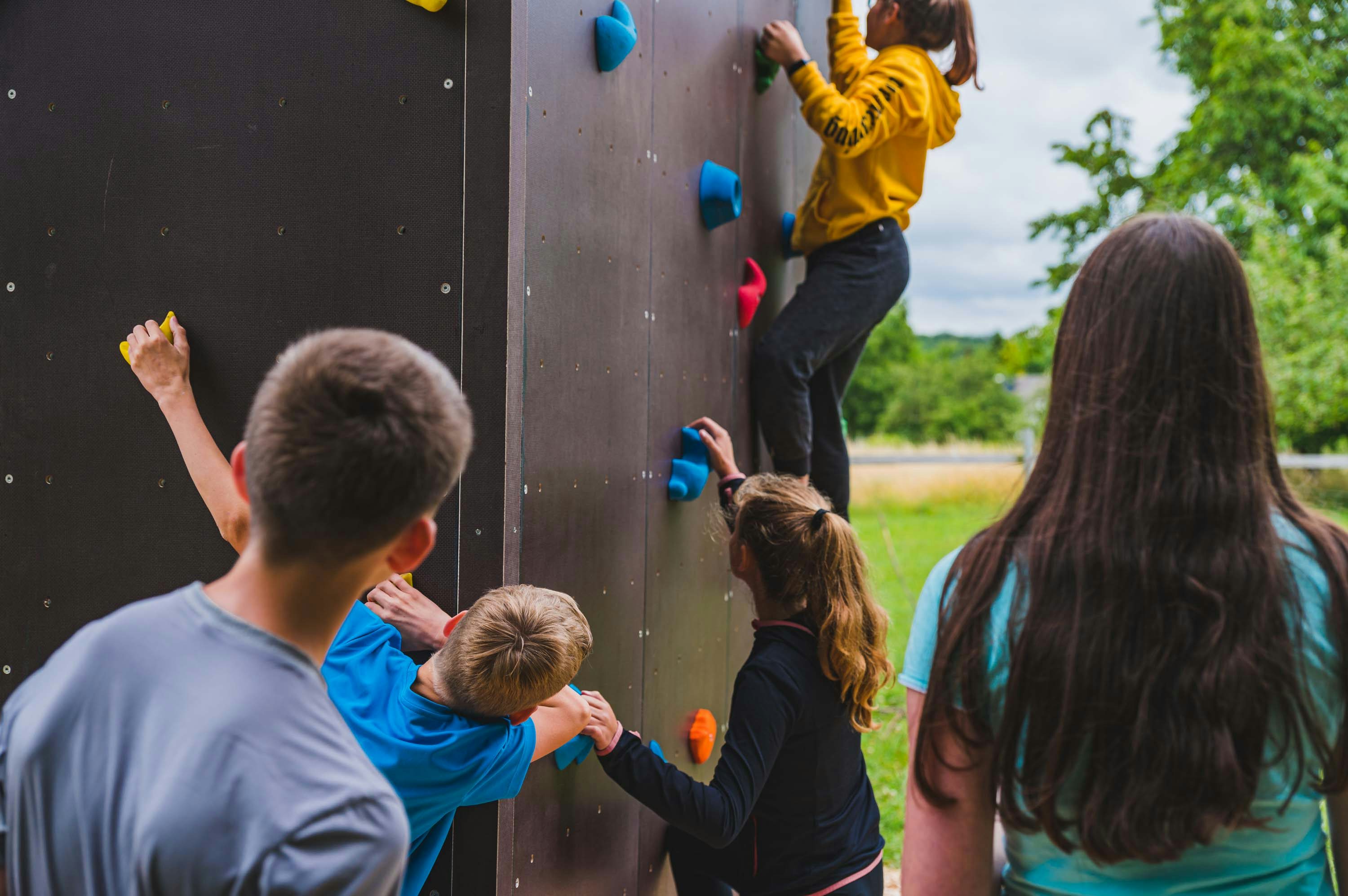 Junge Menschen Bouldern und geben einander Tipps