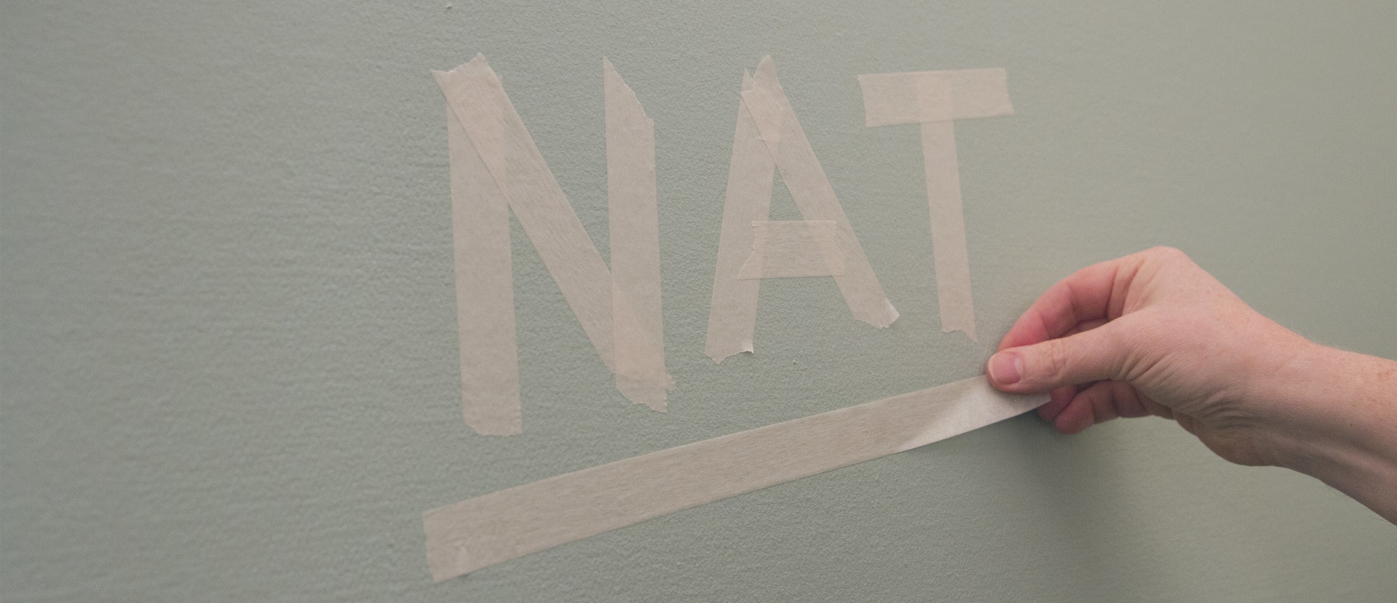 Een geschilderde wand met het woord 'nat' gemaakt van afplak-tape