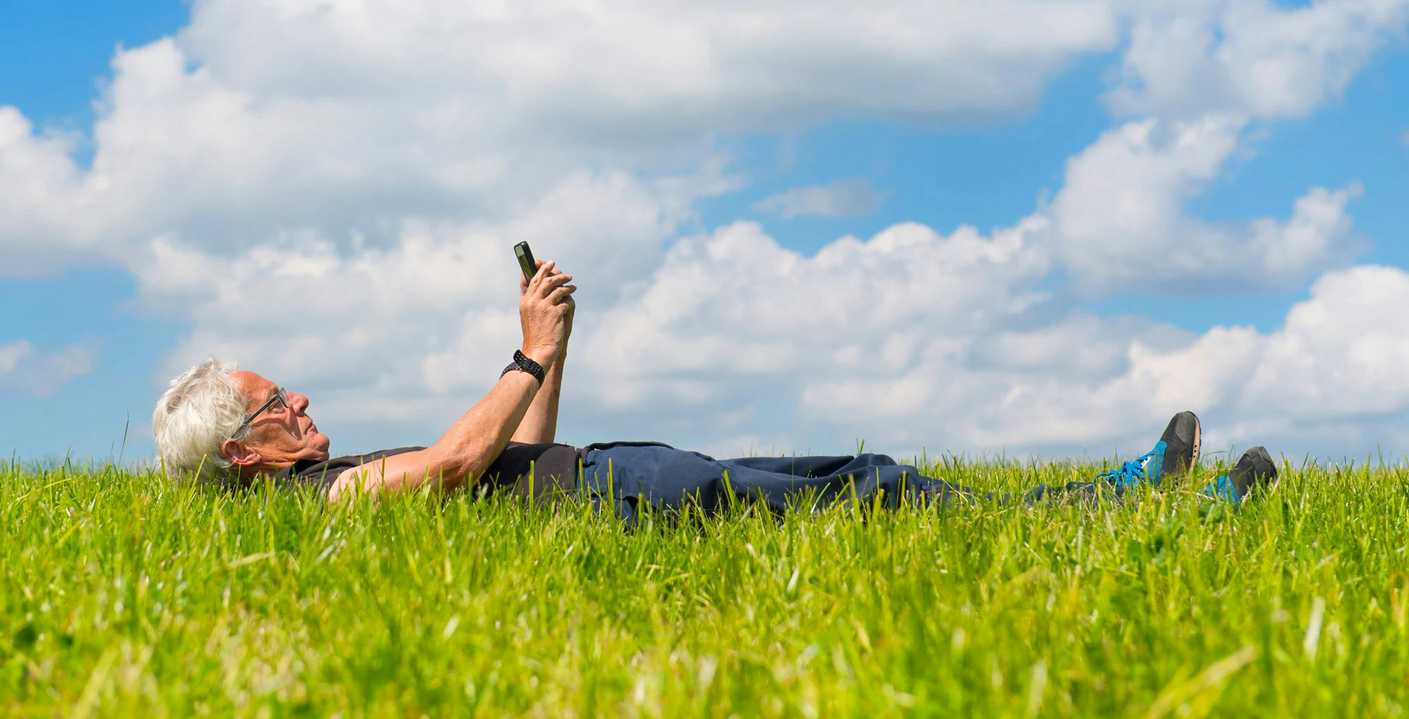 Man ligt in weiland met smartphone