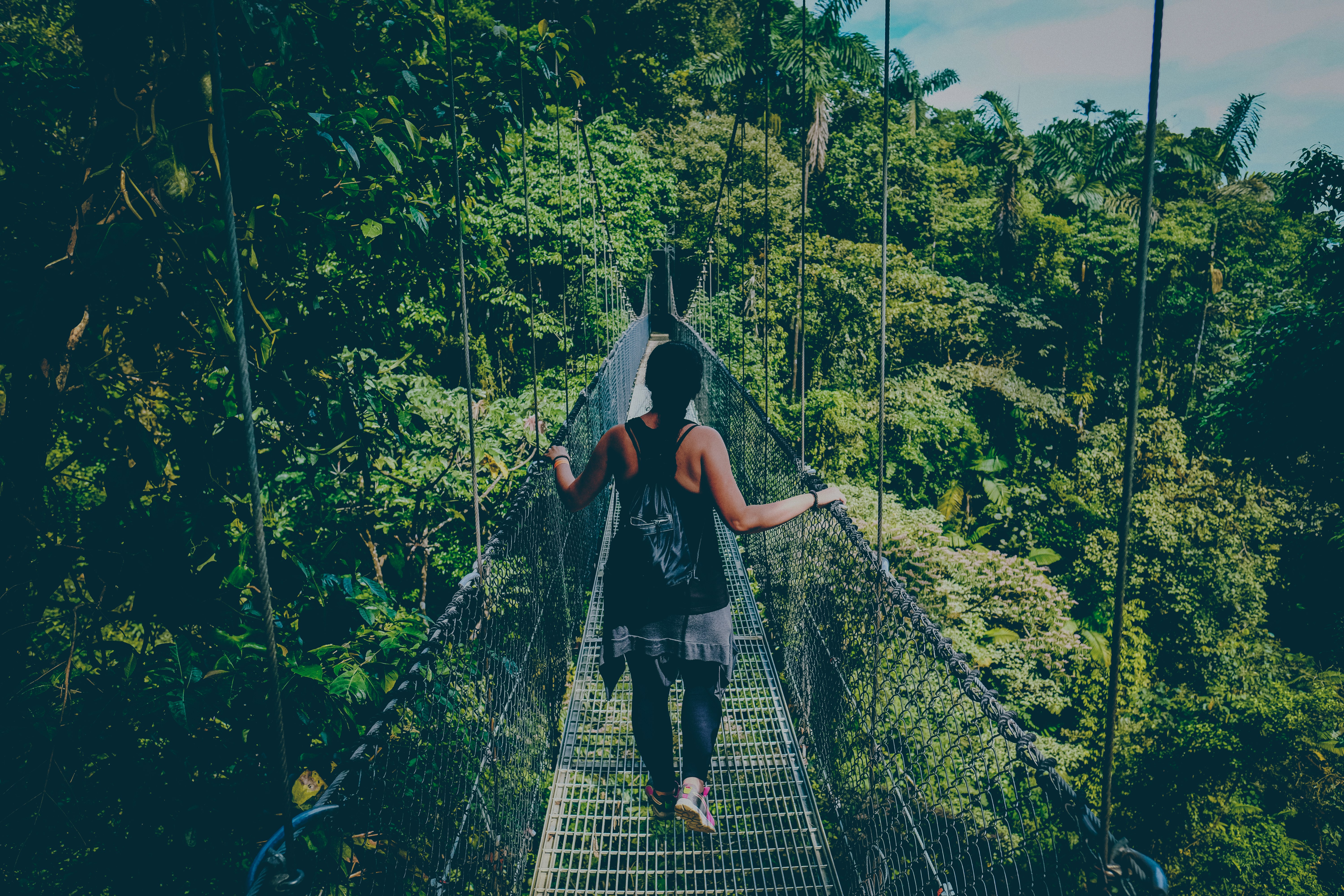 vrouw loopt op hangbrug in het bos