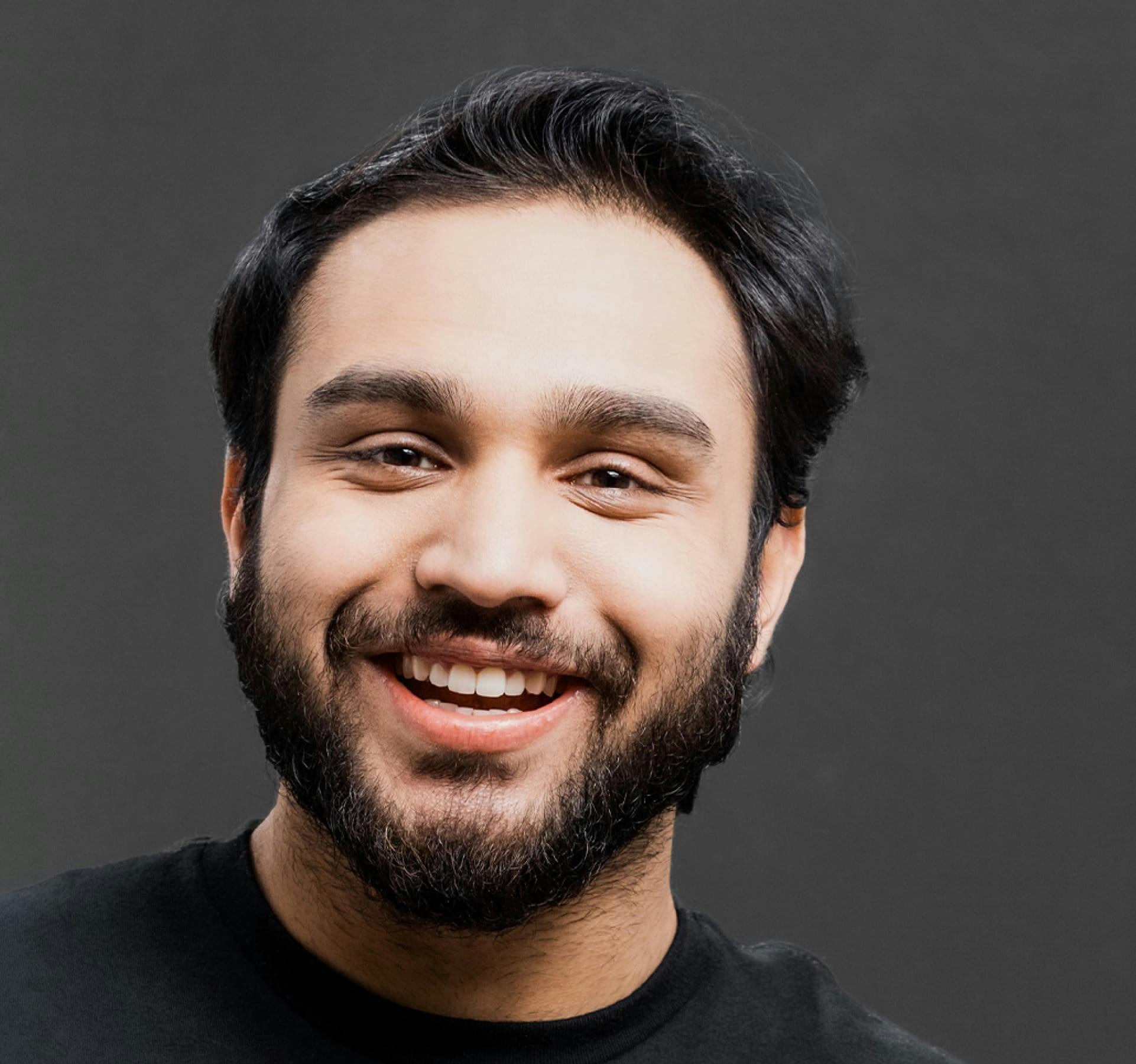 Man with dark moustache and beard smiling