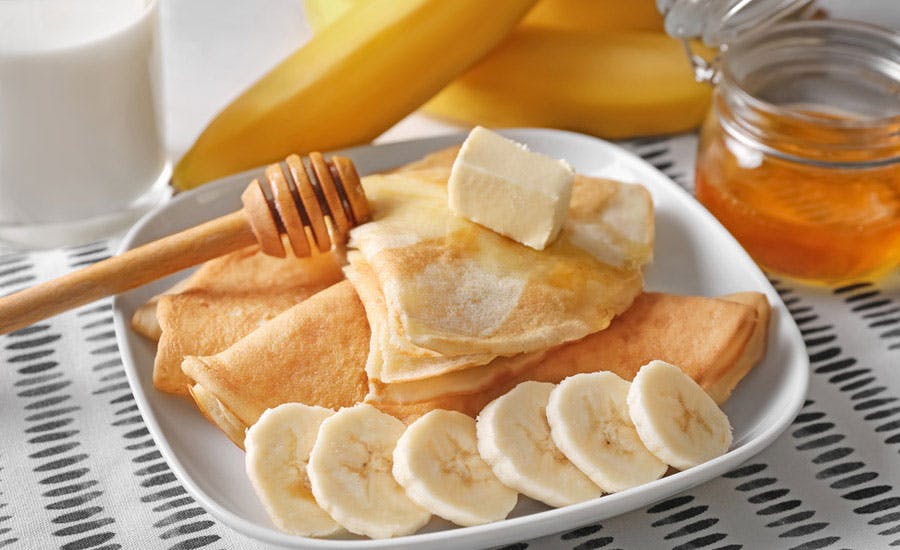 üzerine bal dökülmüş ve muz dilimleri serpilmiş krep