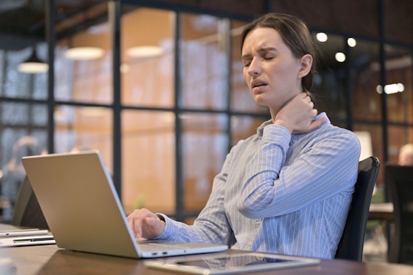 Employee with a sore back sitting at her desk in the office