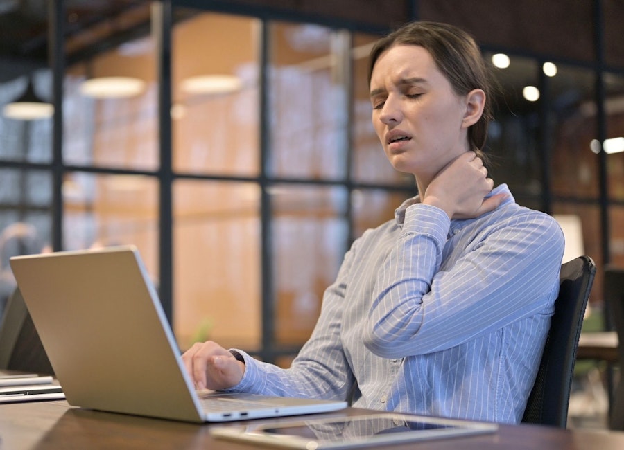 Employee with a sore back sitting at her desk in the office