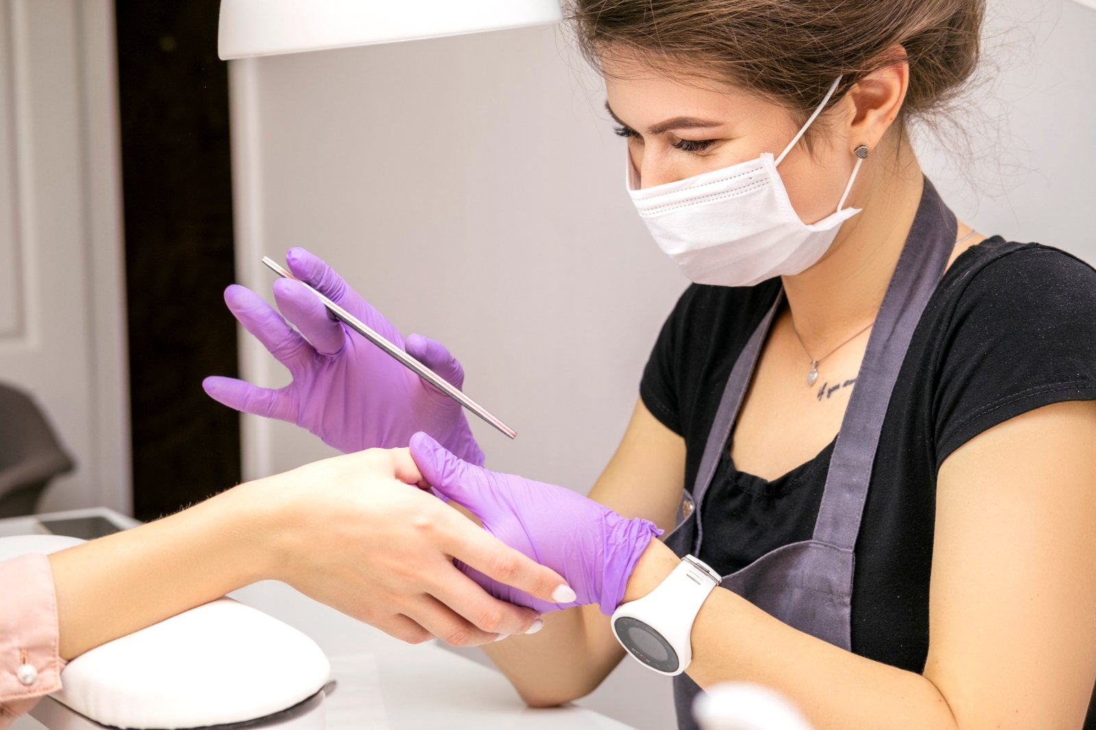 Nail technician providing manicure in a clients home