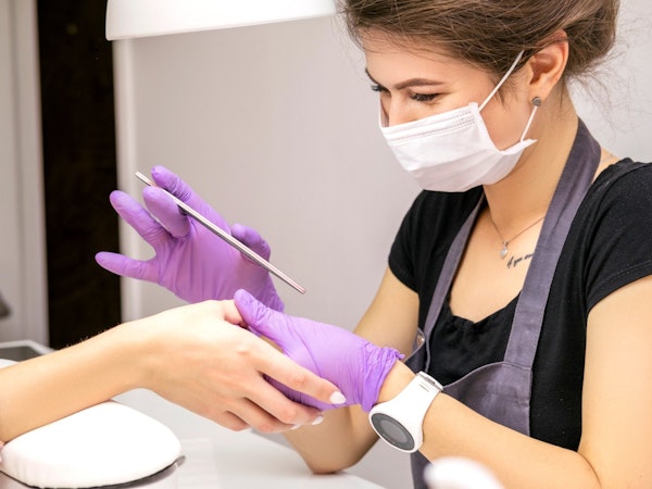 Nail technician providing manicure in a clients home