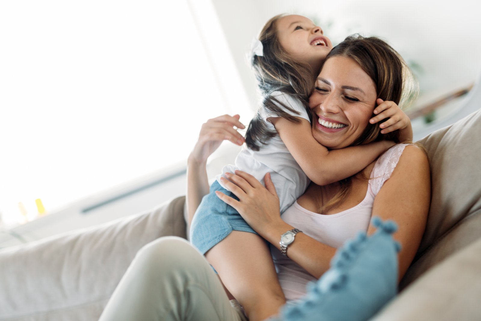 Mum at home on the sofa playing with her daughter