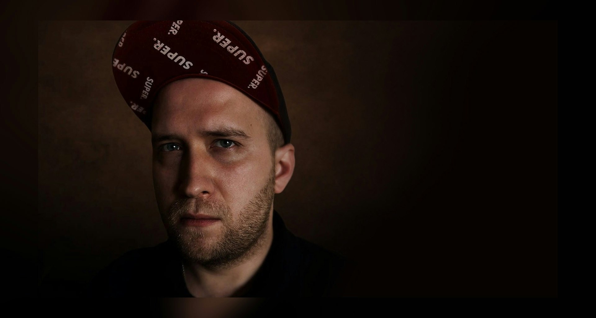 Zdjęcie profilowe na którym jest mężczyzna w czapce z daszkiem na ciemnym tle