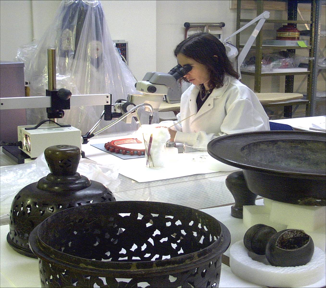 Museum conservator uses a microscope to examine an object