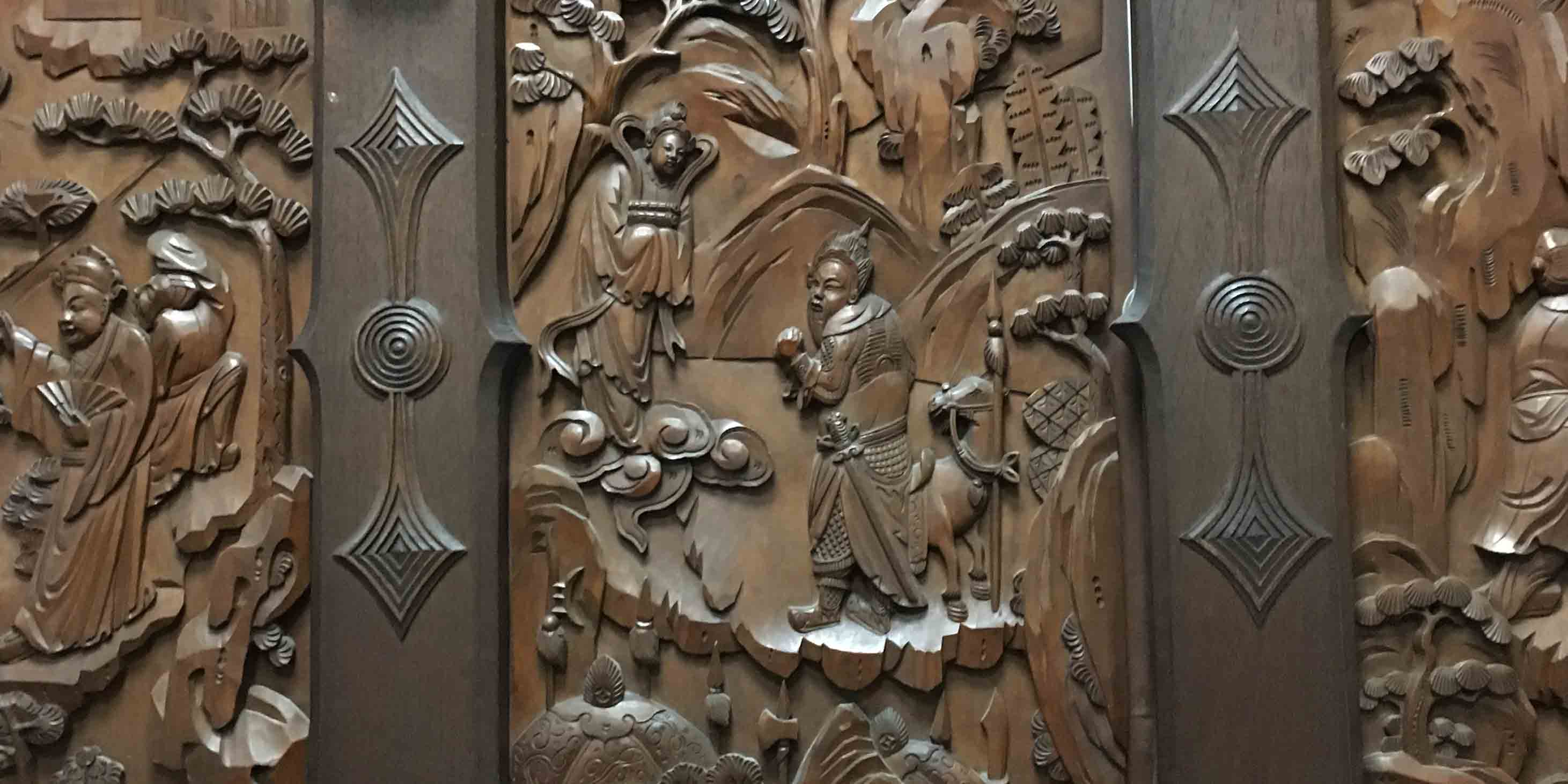 Detail of intricate wood carving, with a man with a sword and a horse depicted