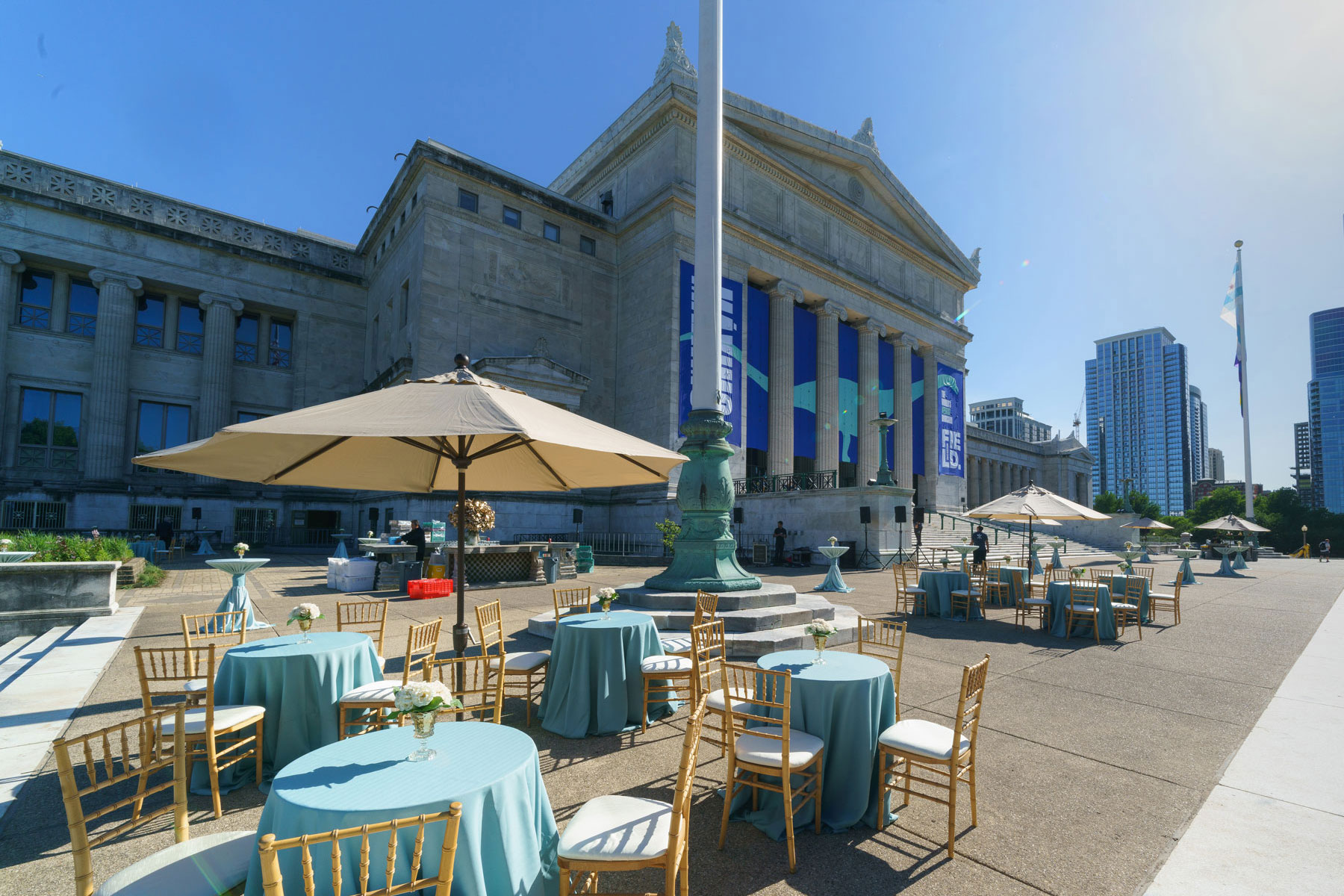 Tables and chairs set up outside the north entrance of the Field Museum on a sunny day.