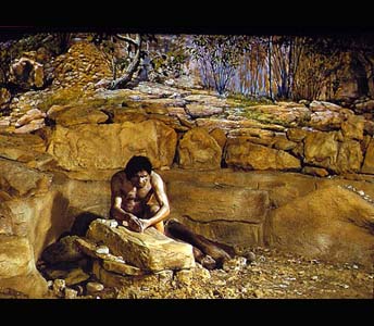 Solutrean sculptor carves a horse on a block of stone. On the shelf behind him are reproductions of the other stone carvings found in Le Roc, France. On the left side the path leads up to a cave, and on the right side, sheltered behind large trees, the entrance to another cave can be seen.
Credit Information:© 1981 The Field MuseumID# CSA77696cPhotographer: Ron Testa
