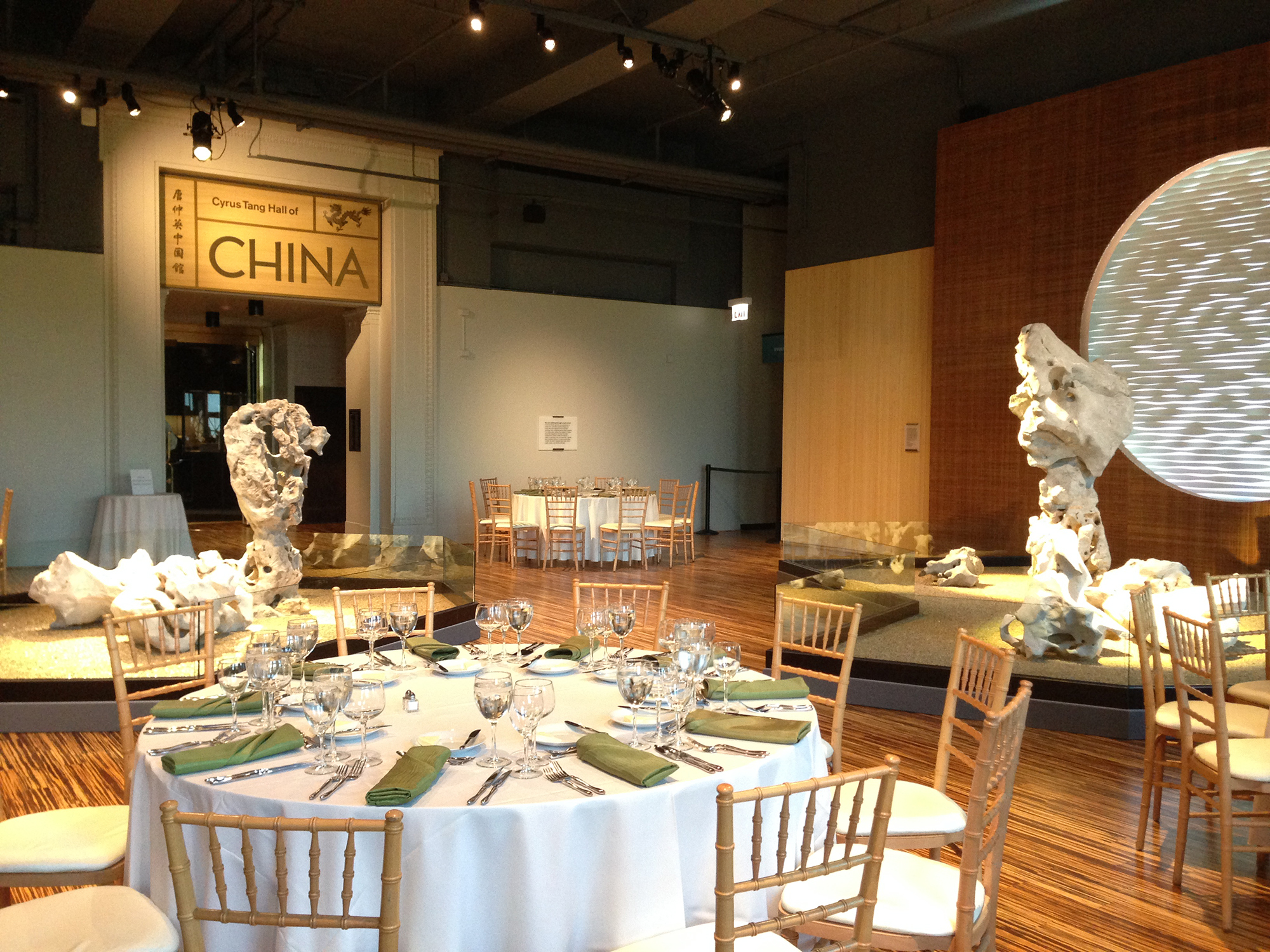 Sue Ling Gin Garden space set up for a dinner, with 10-person tables and chairs, white table cloths, and place settings.