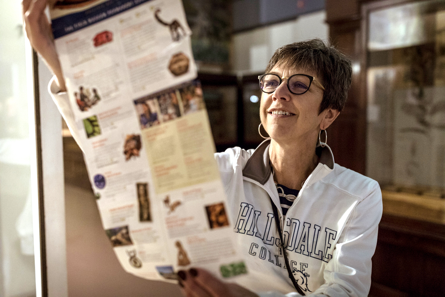 A woman wearing glasses reads a map that's she's unfolded in front of her.