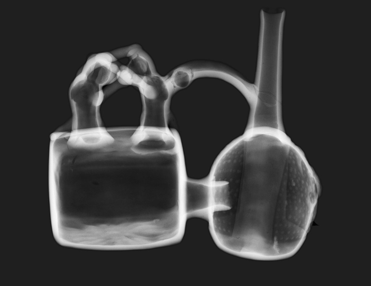 Ceramic vessel, Peru, Chimú Culture (1100-1400 CE): X-ray shows the complex interior structure of the pot: two chambers joined by hollow tubes with a hollow spout and the hollow construction of the two monkeys, each grasping the other's head, on top of the square chamber. Cracks in the handle covered in previous restorations are also visible.