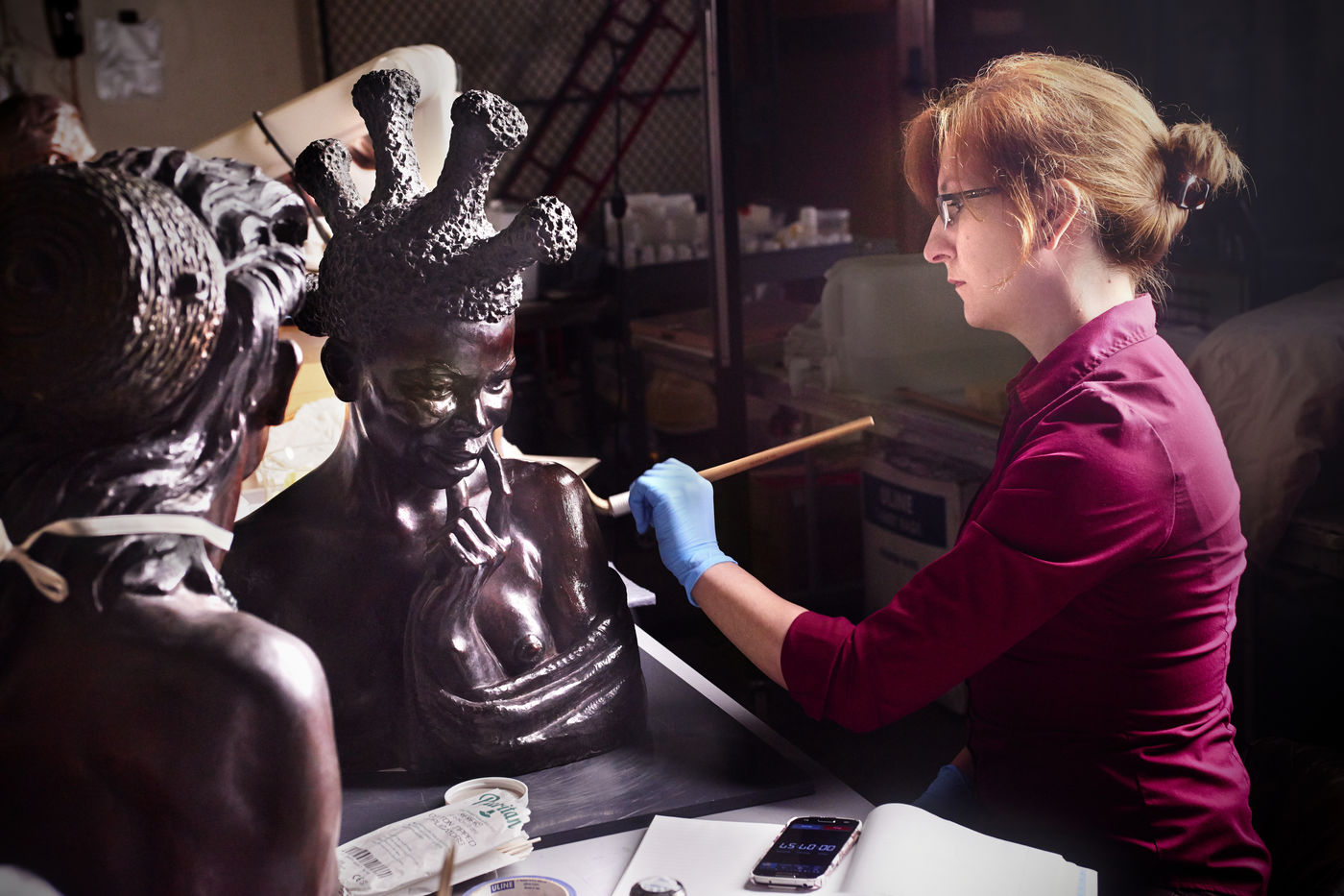 Conservation Assistant Allison Cassidy treats a bust portraying a woman from Sudan, created by artist Malvina Hoffman.