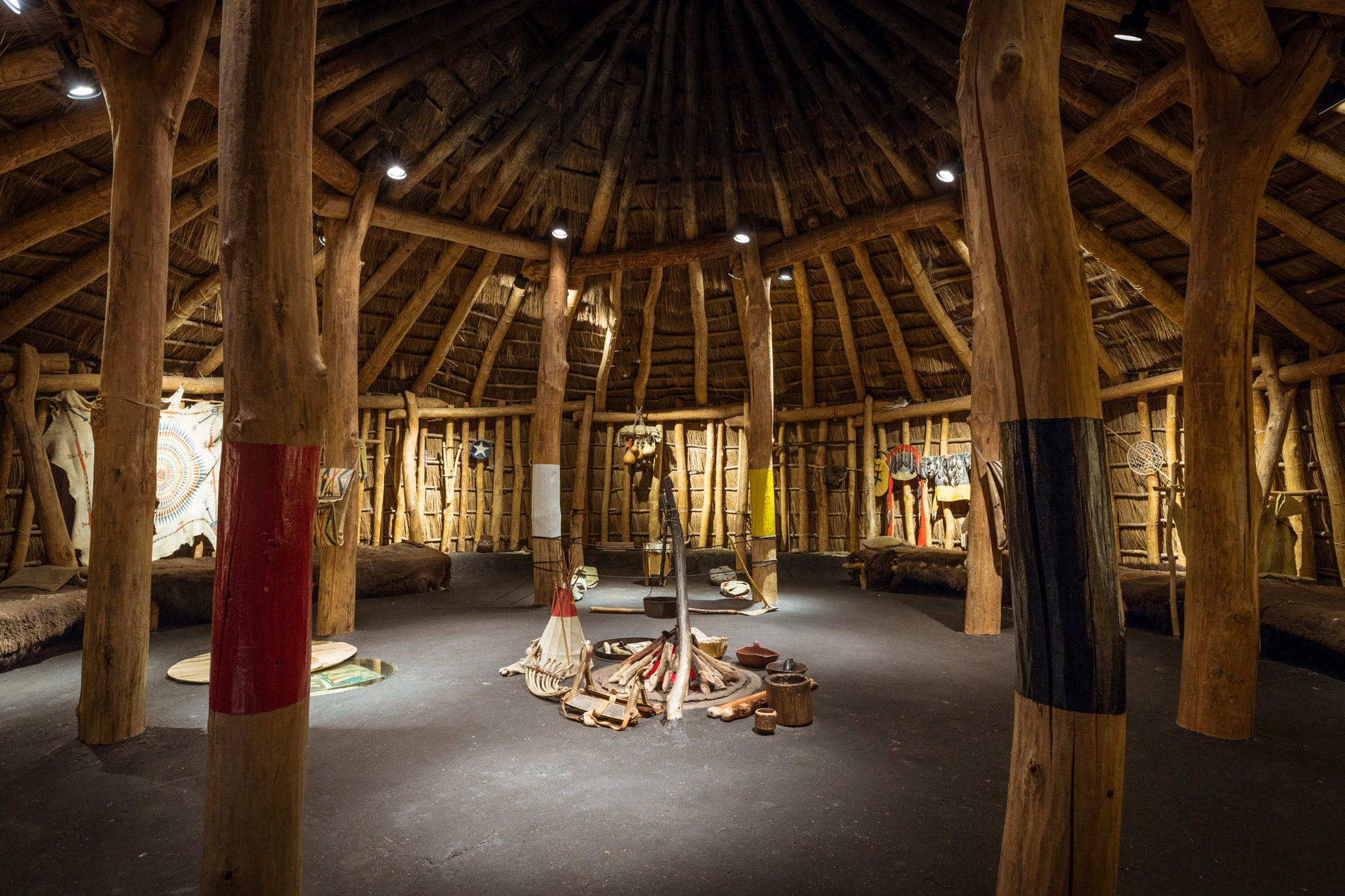 View of the circular interior of the Pawnee Earth Lodge, with various replica objects displayed around the circular hearth in the center and on the walls.