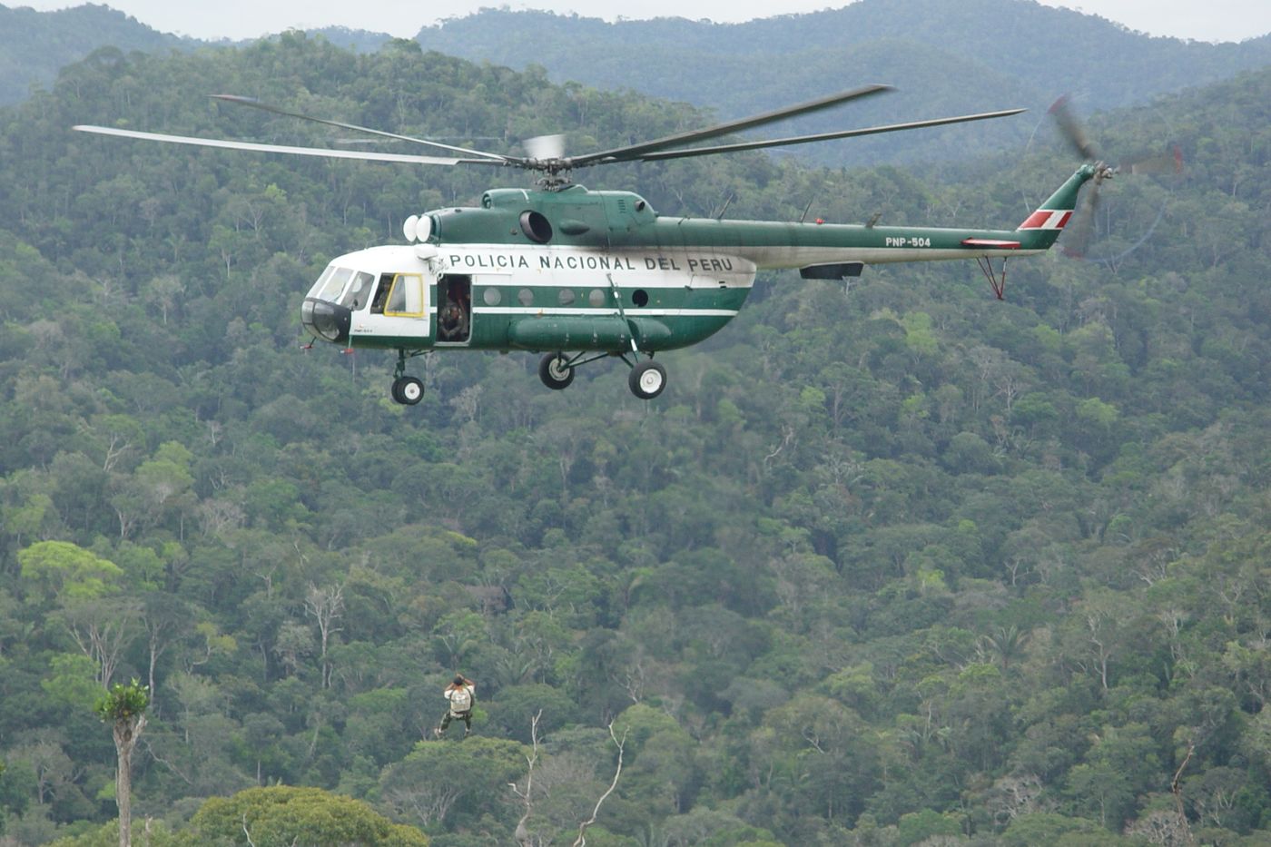 A scientist suspended from a helicopter is cabled down into the Sierra del Divisor mountain range in Peru in 2005.