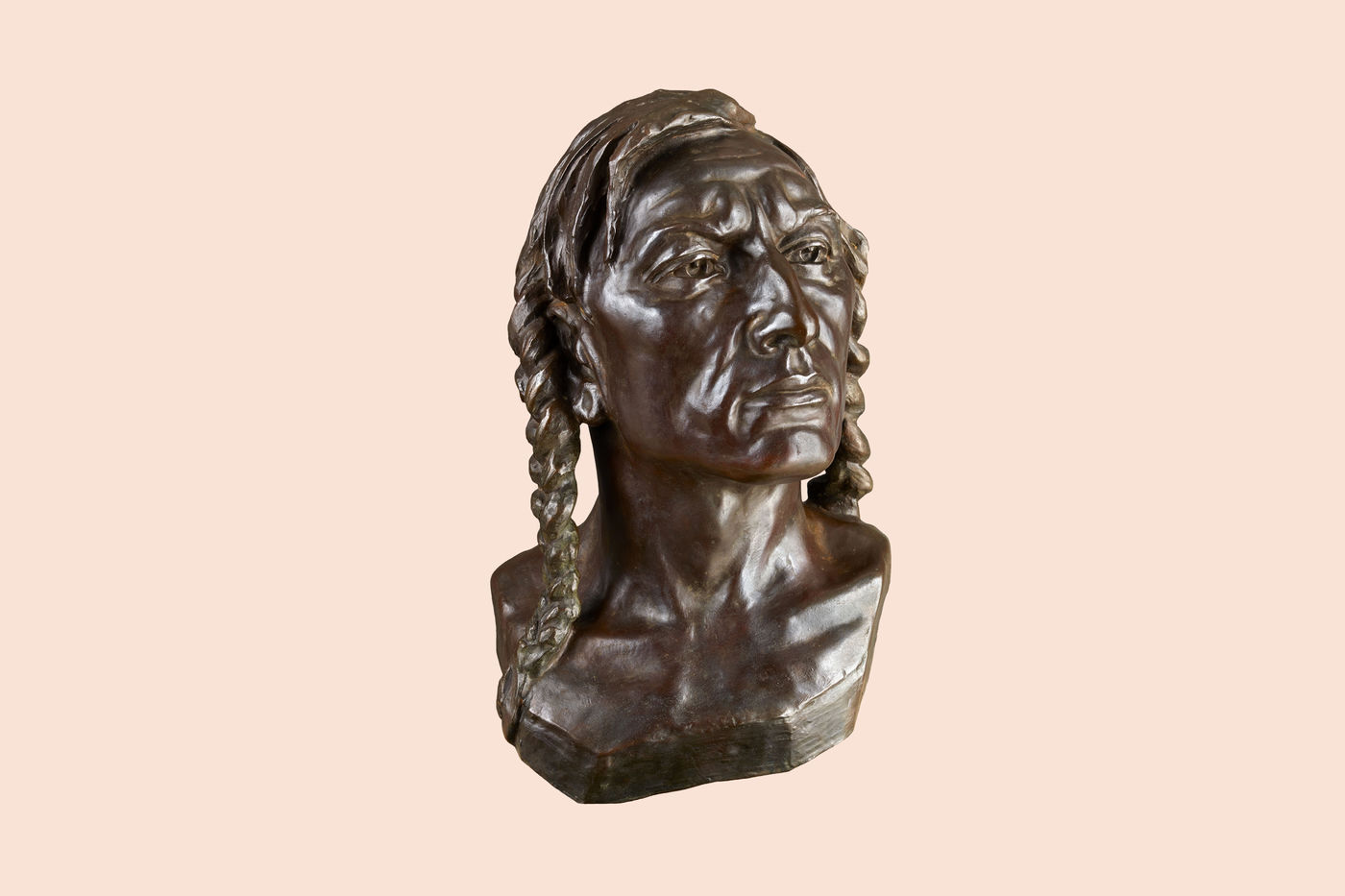 Bronze bust of a Crow man. His head is turned slightly to his left and his chin is very slightly raised. He has two long braids and wrinkles on his brow.