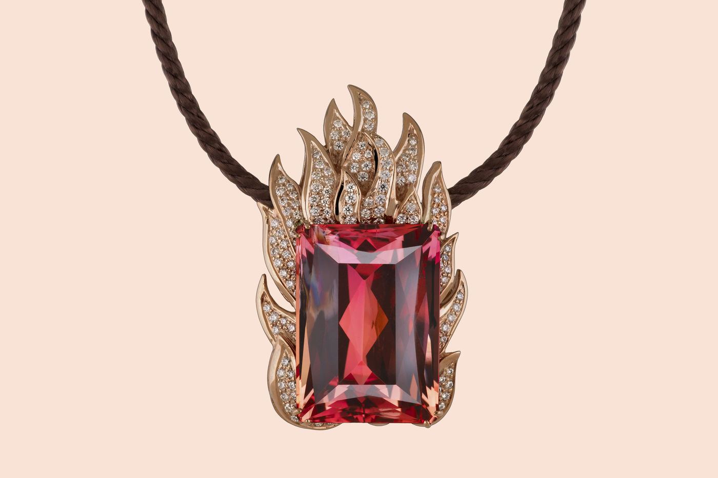 Necklace featuring a large, red gem. Flames made from rose gold and inset with diamonds surround the ruby topaz gem. 