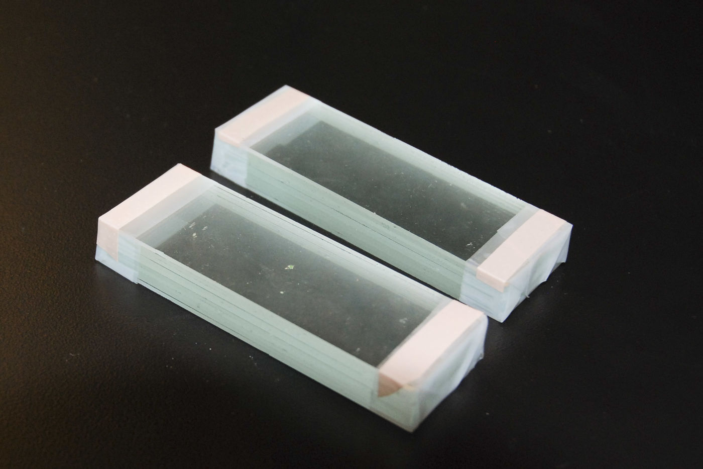 Two glass blocks. Each is 10 glass microscope slides held together with tape wrapped around the ends. Strips of Band-Aid fabric are applied to the top to provide some friction between the block and whatever you put on top of it.