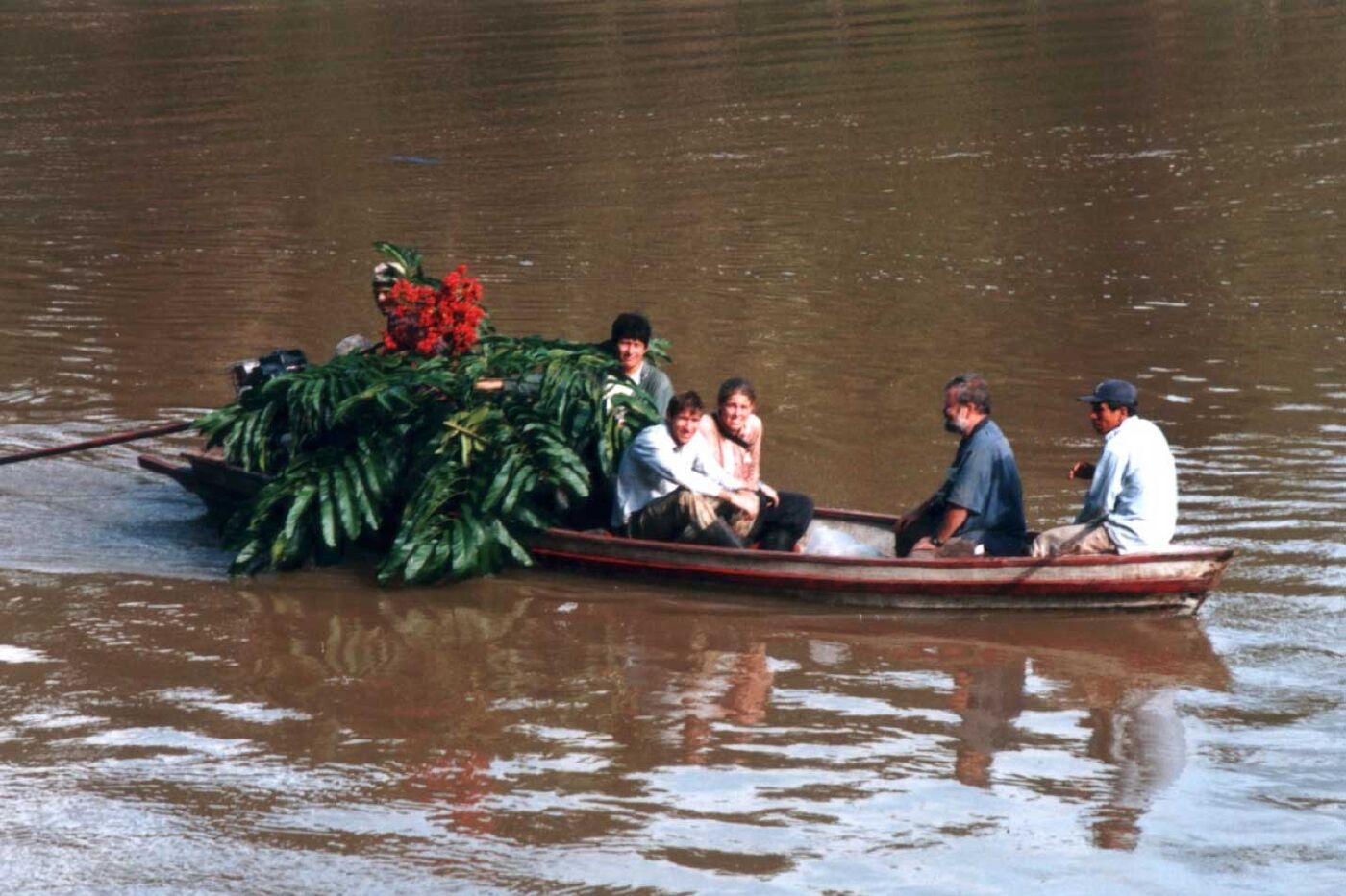 A group of people transporting plant specimens in a canoe on the river.