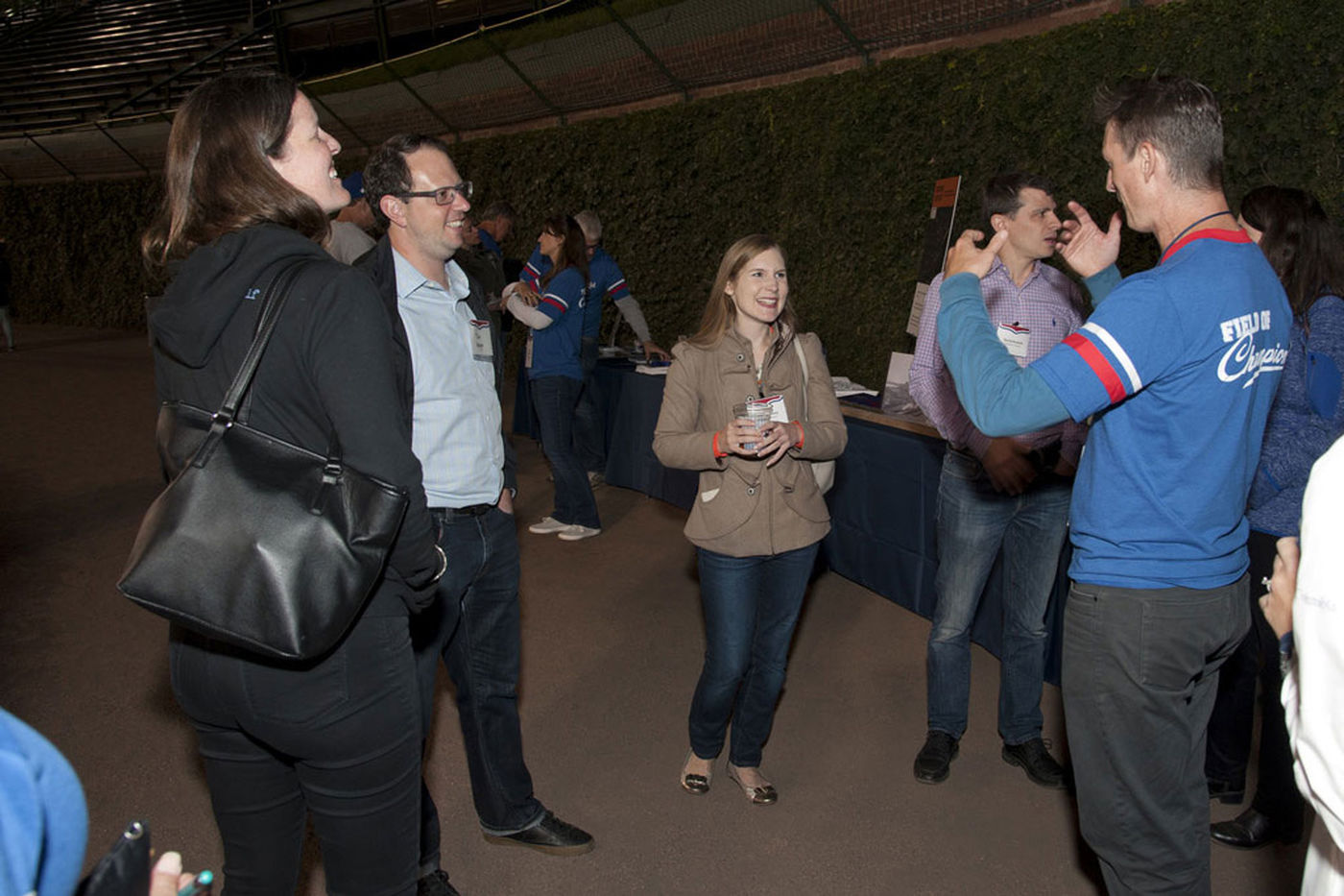 A group of President’s Leadership Council members gather in Wrigley Field for an event. They stand in a circle, and man on the right holds his hands up as he speaks. 