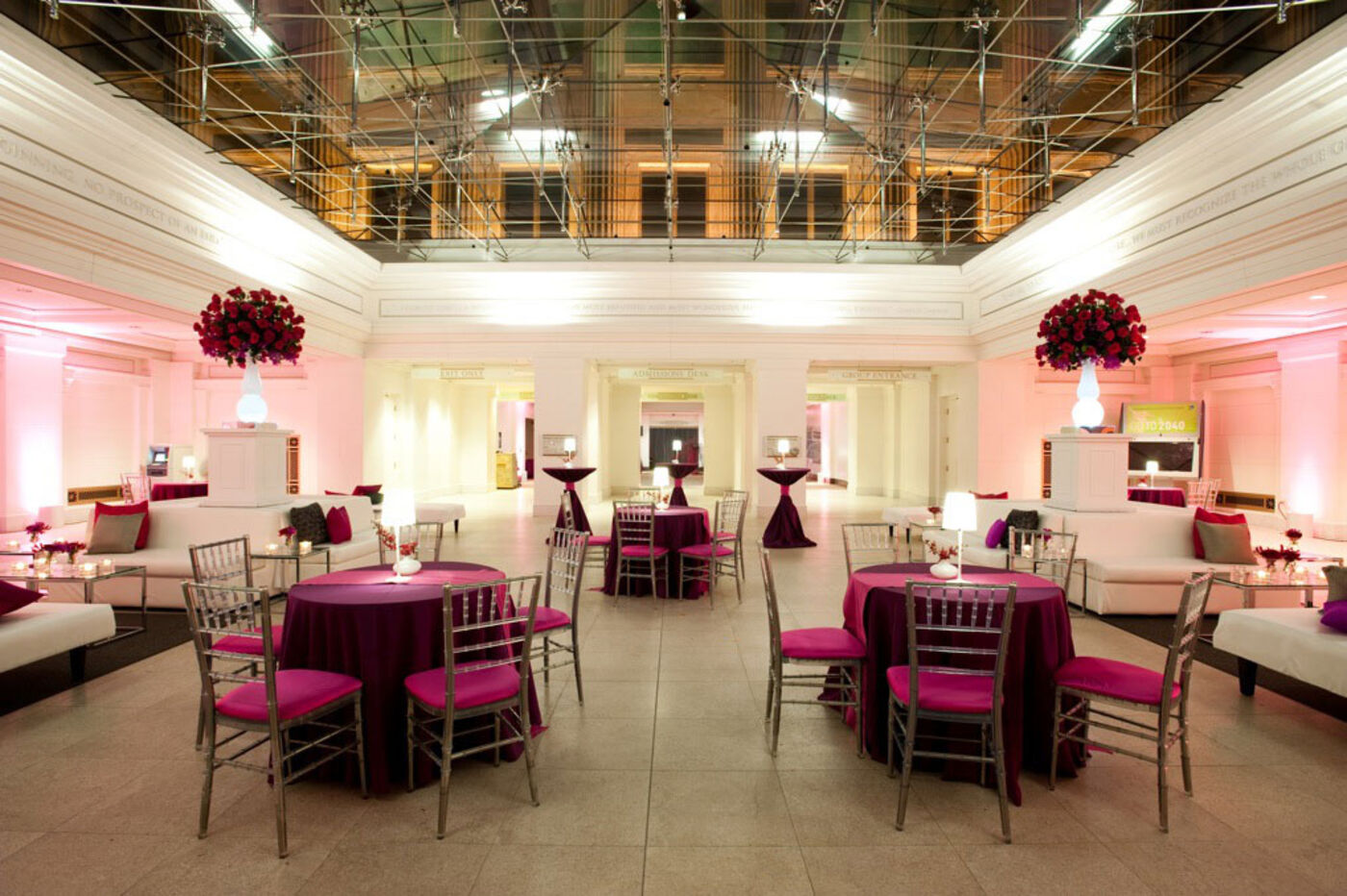 Tables, chairs and other seating set up for a special event in a glass ceiling space.