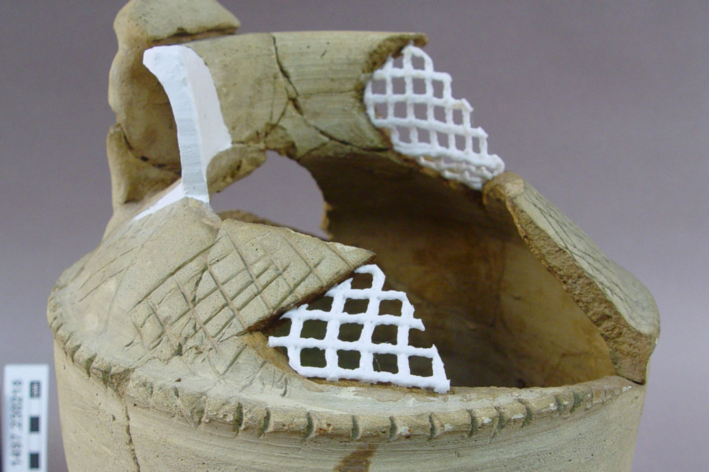View of a piece of pottery undergoing conservation, with mesh supports visible. 