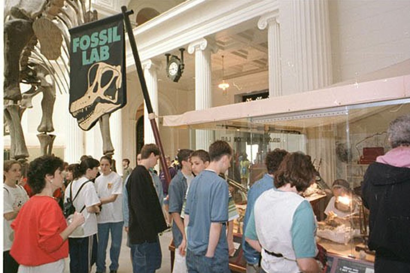 A public viewing lab setup in the Stanley Field Hall with visitors looking over fossil preparators at work.