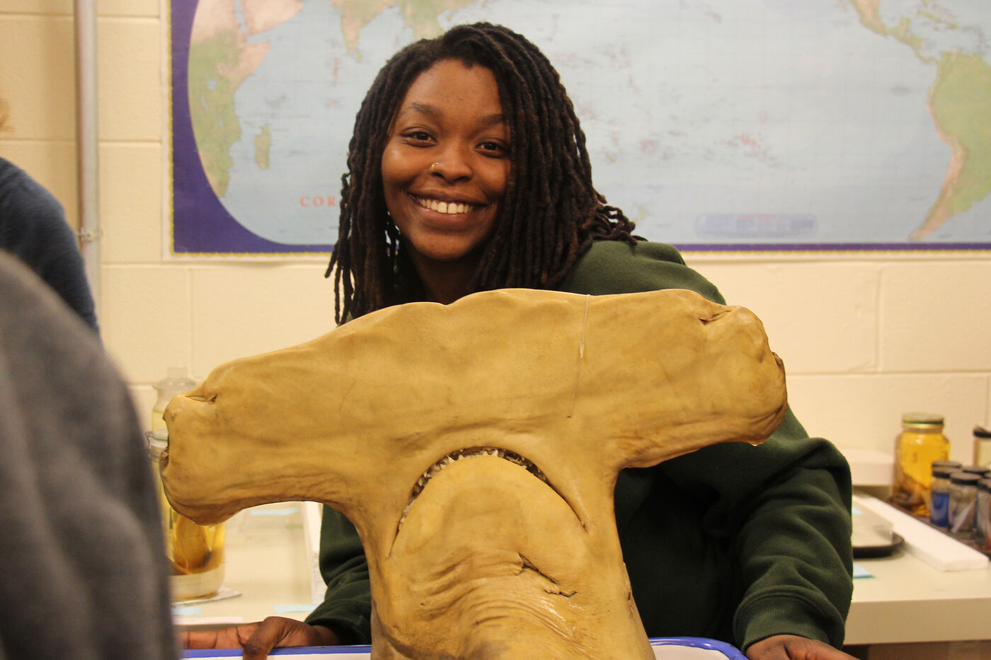 A teen smiles while holding a preserved hammerhead shark