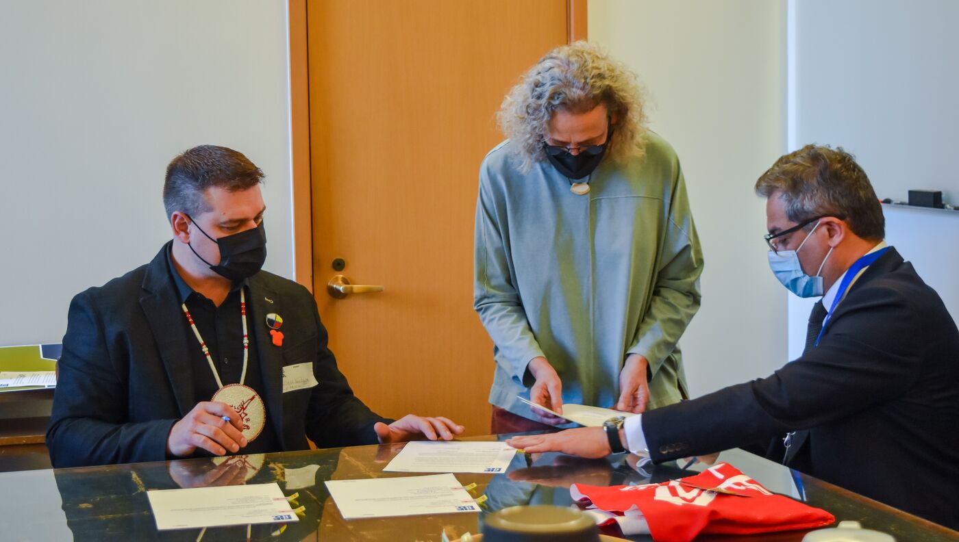 Three people around a table looking at and signing documents.